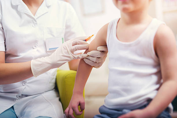 Pediatrician makes vaccination to small boy stock photo