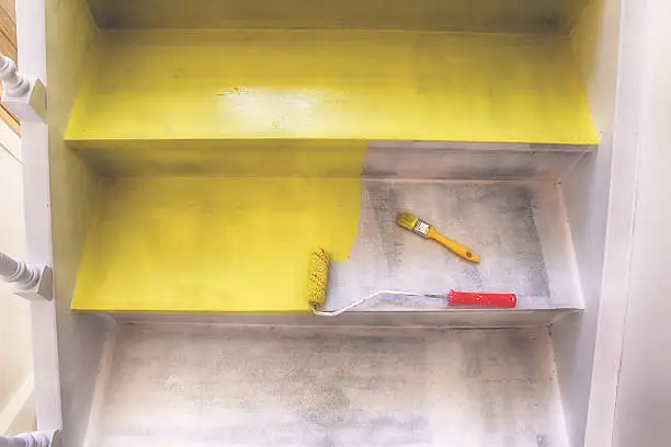 Painting stairs with brush and roller in yellow