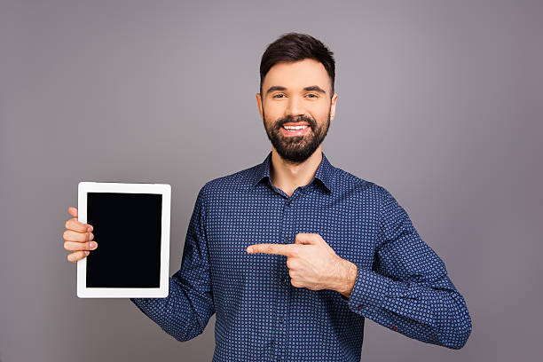istock Handsome happy young businessman pointing on screen of tablet 636351918