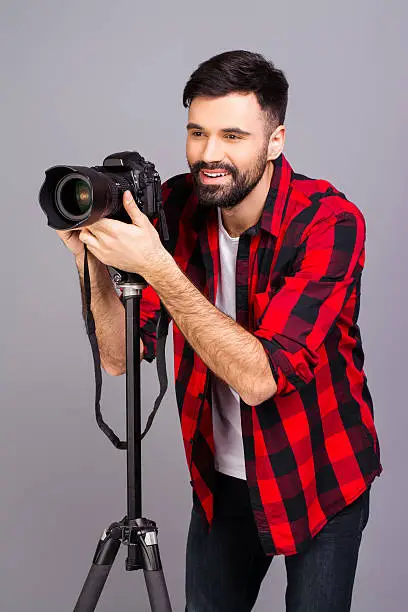 Young professional photographer with digital camera  taking photos