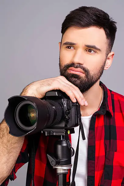 Portrait of sad man with camera thinking about photo concept