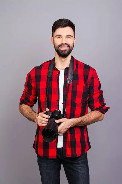 Handsome young bearded happy man holding professional camera