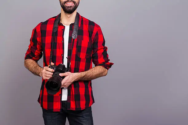Close up photo of man in red checkered shirt holding camera