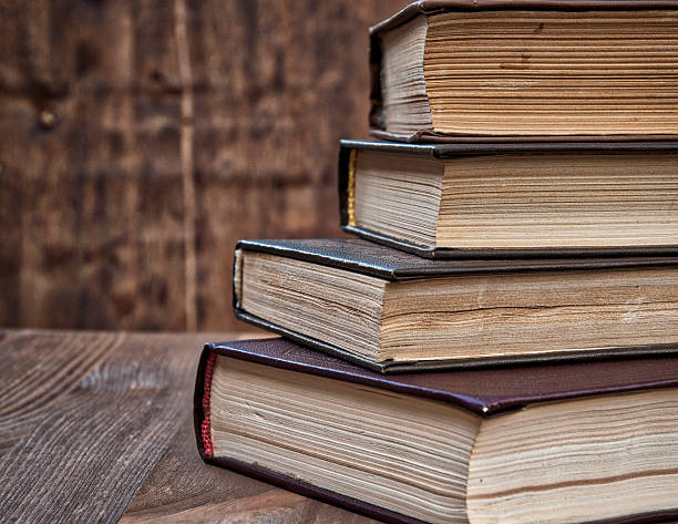istock stack of old books on a brown wooden background 636355386