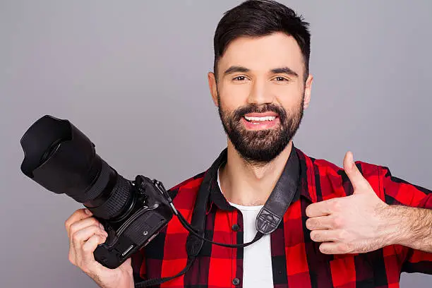 Happy man with professional camera showing thumb up