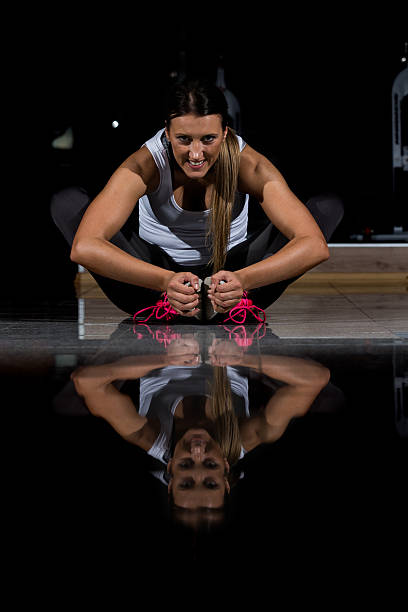 mulher em uma academia se exercitando, fazendo flexões. fundo escuro - human muscle flash - fotografias e filmes do acervo