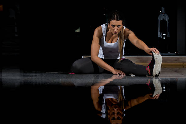 mujer en un gimnasio haciendo ejercicio, haciendo flexiones. fondo oscuro - human muscle flash fotografías e imágenes de stock