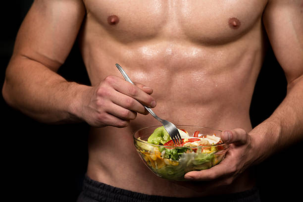 gesunder bodybuilding mann hält eine frische salatschüssel - fashion model beautiful power action stock-fotos und bilder