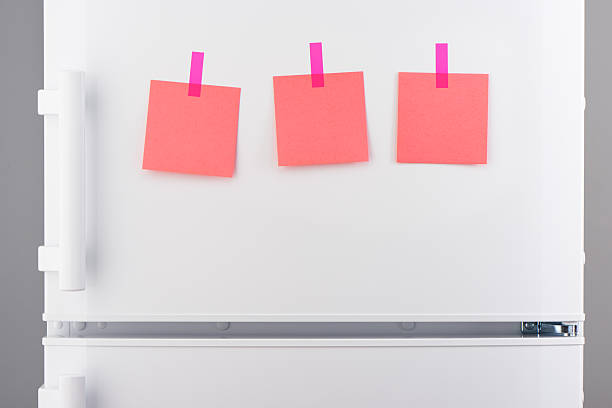 istock Pink paper notes attached with stickers on white refrigerator 636372188