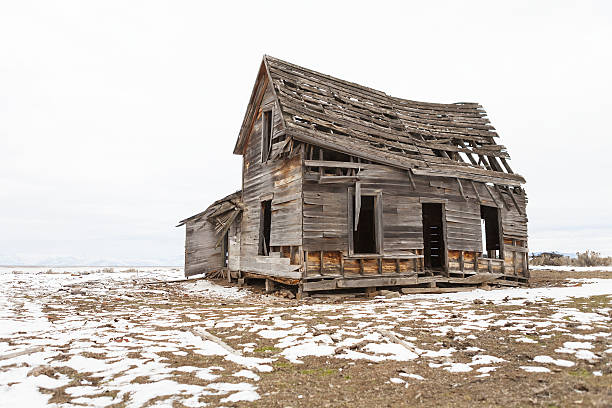 Old abandoned farm house in winter with snow.