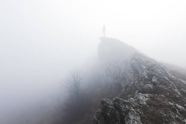 Man standing alone in the fog in mountains