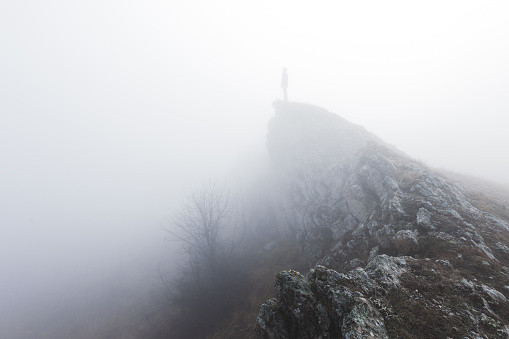 Man standing alone in the fog in mountains