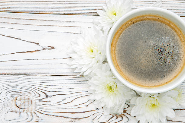 istock cup of coffee and flowers on light wooden table 636377762