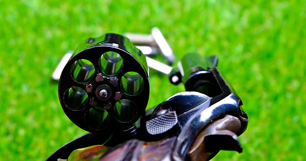 istock Revolver gun in hand on grass background 636383418