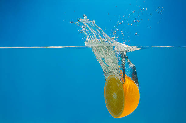 istock Orange splashing in water with blue background 636394494