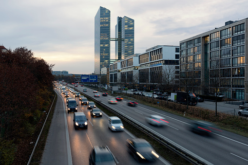 Busy road with modern office building in Munich, Germany, during the golden hour