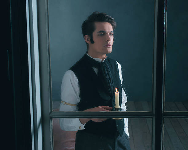 istock Retro dickens style man with candlestick looking out rainy window. 636399852