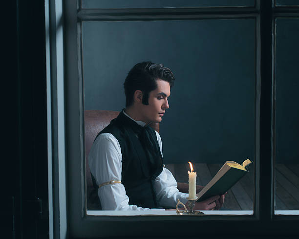 ретро викторианский человек читает книгу при свечах сидя у окна. - scrooge стоковые фото и изображения