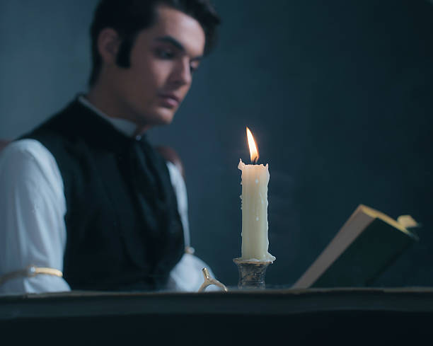 istock Candlelight by window with blurred retro victorian man reading book. 636400002