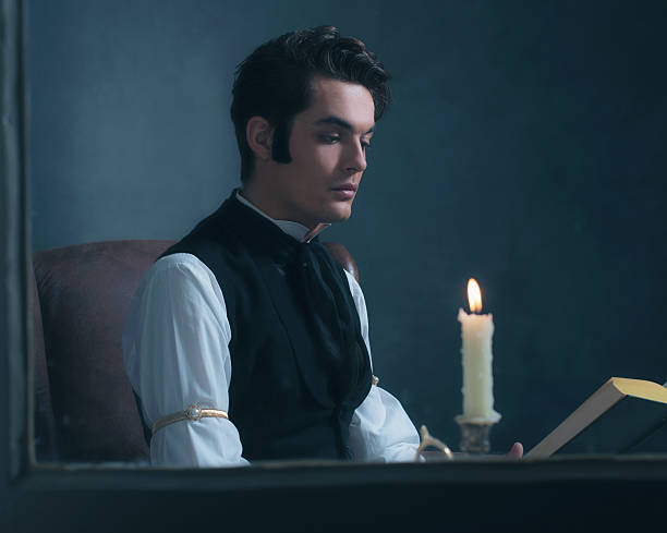 istock Retro victorian man reading book by candlelight sitting by window. 636400052