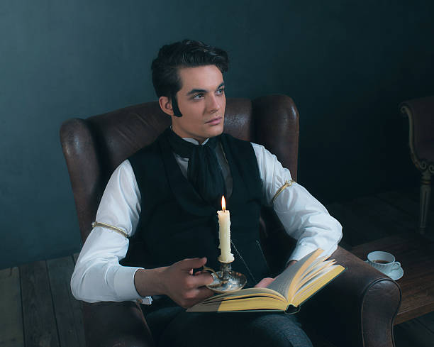 istock Retro victorian dickens style man reading book by candlelight. 636400600