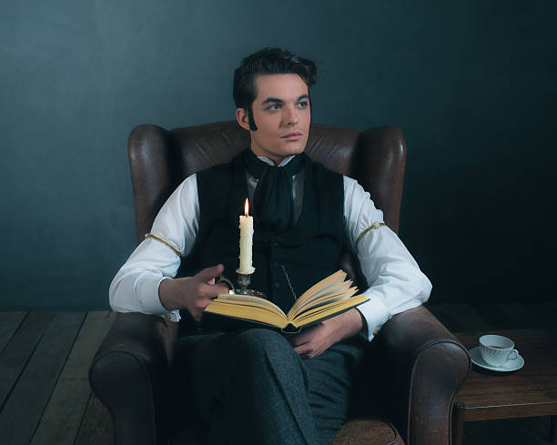 istock Retro victorian dickens style man reading book by candlelight. 636400614