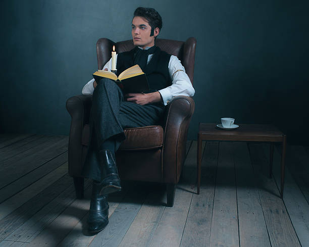 istock Retro victorian dickens style man reading book by candlelight. 636400640