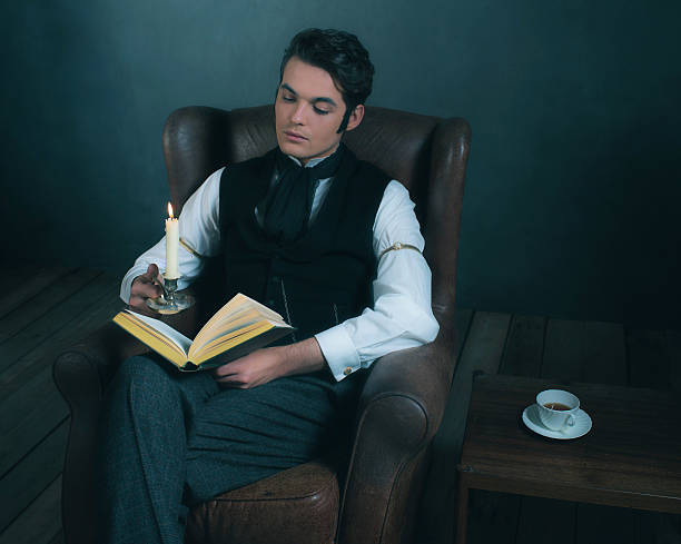 istock Retro victorian dickens style man reading book by candlelight. 636400672