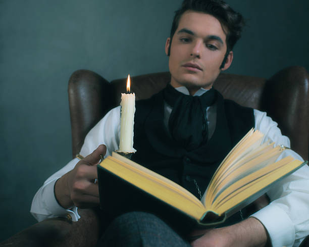 istock Retro victorian dickens style man reading book by candlelight. 636400680