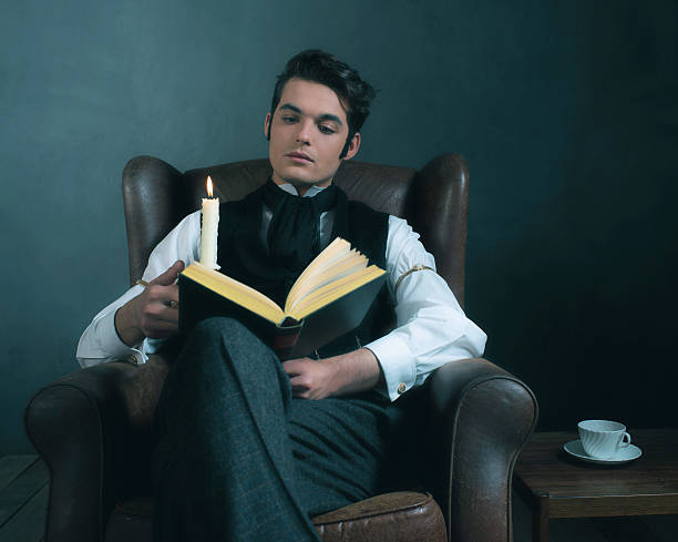 istock Retro victorian dickens style man reading book by candlelight. 636400720