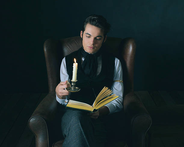 istock Retro victorian dickens style man reading book by candlelight. 636400730