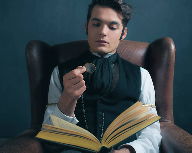istock Vintage victorian dickens style man reading book with magnifying glass. 636400738