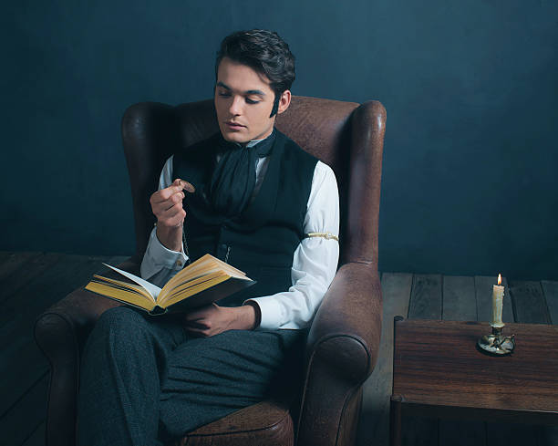 istock Vintage victorian dickens style man reading book with magnifying glass. 636400756