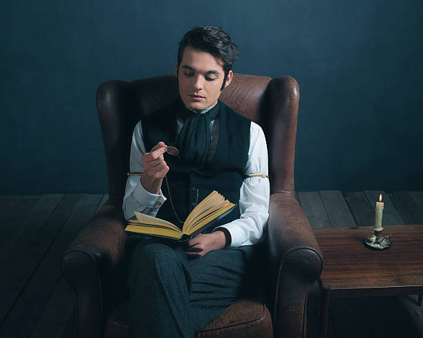 istock Vintage victorian dickens style man reading book with magnifying glass. 636400774