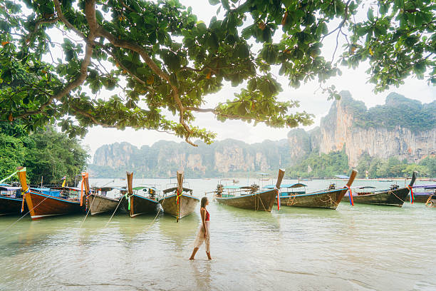 mulher perto dos barcos na praia na tailândia - railay - fotografias e filmes do acervo
