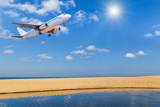 passenger airplane flying above tropical beach in andaman sea on  blue sky background with sunlight  travel destinations concept