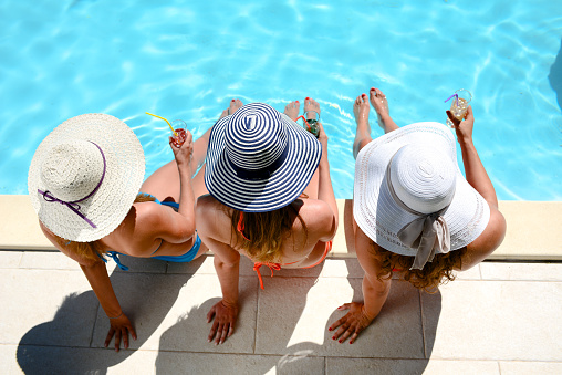 young woman sun hat sitting poolside resort pool summer holiday