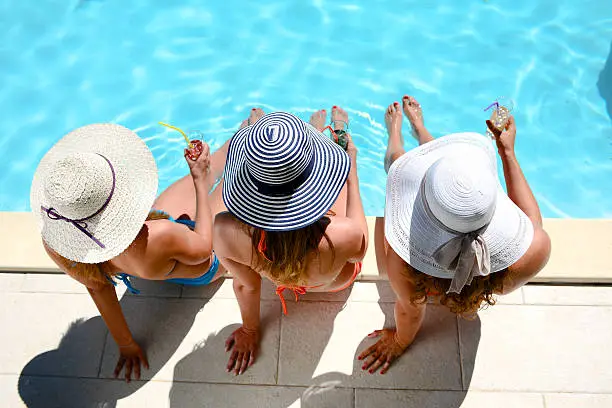 Photo of young woman sun hat sitting poolside resort pool summer holiday