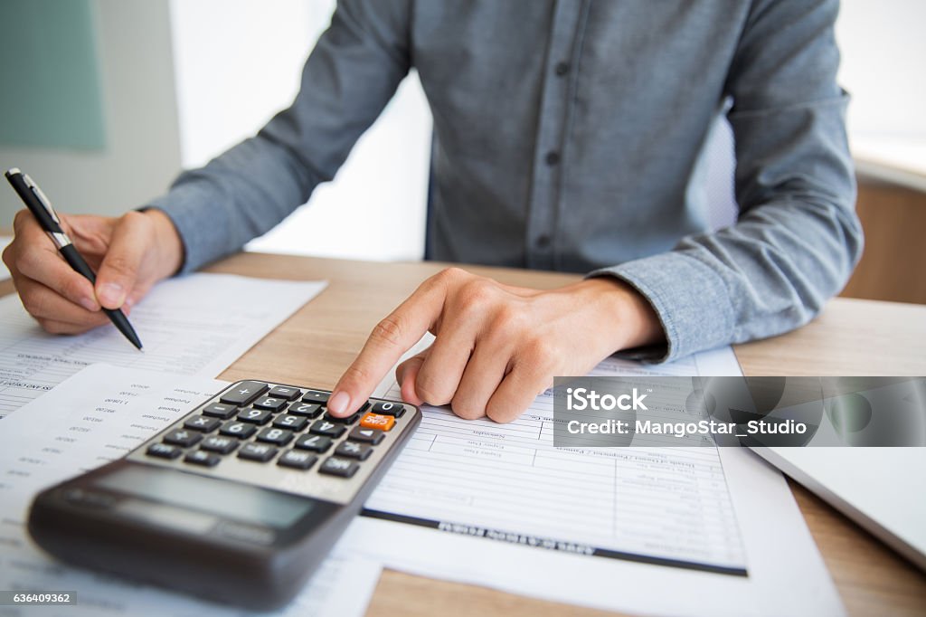 Accountant examining financial report Unrecognizable accountant examining financial report. Male hands using calculator at desk. Businessman preparing annual report in office. Paperwork concept Preparation Stock Photo