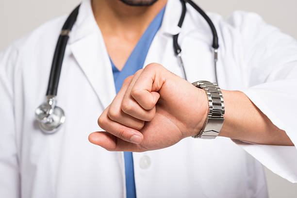 Doctor looking at his watch stock photo