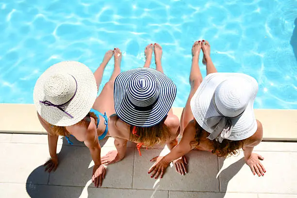 Photo of young woman sun hat sitting poolside resort pool summer holiday