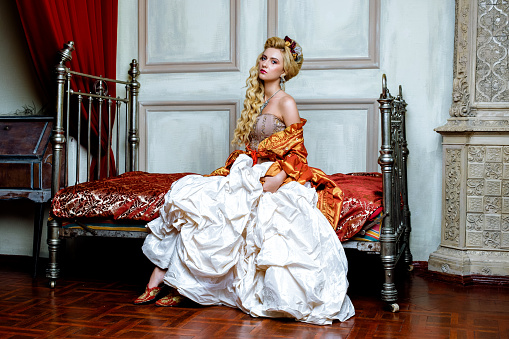 Retro baroque fashion blonde woman wearing gold dress.