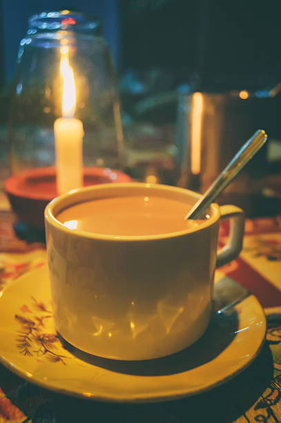 Candlelight dinner and traditional Indian hot drink - masala tea in romantic tropical cafe on the beach, Goa, India. Spiced tea with milk. Soft selective focus and blurred background