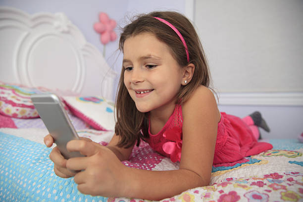 istock Little girl with smart phone lying in a bed 636417262
