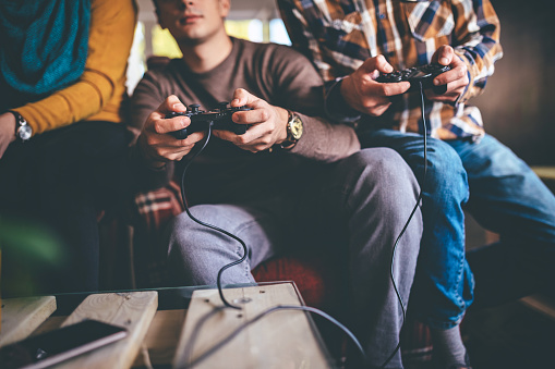 Group of three friends playing video games in office after work