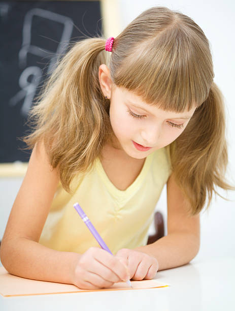 istock Little girl is writing using a pen 636420684