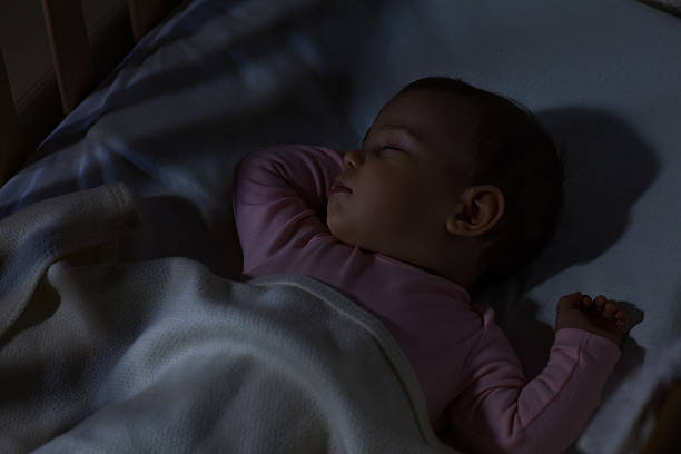 Baby Sleeping on the bed Adorable baby sleeping at night. Little girl in pajama taking a nap in dark room. baby sleeping bedding bed stock pictures, royalty-free photos & images