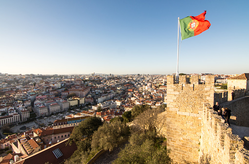 Lisbon, Portugal - March 11, 2016: The Portugese flag flies from the walls of Castelo de Sao Jorge above the cityscape of Lisbon.