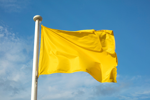 Close up of yellow flag at the beach, warning of sea conditions to bathers.