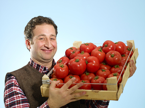 Young farmer holding tomato.